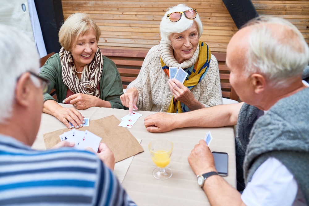 Senior friends playing card together at their assisted living communities